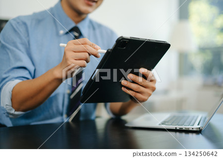 Confident businessman working on laptop, tablet and smartphone at her workplace Confident businessman working on laptop, tablet and smartphone at her workplace 134250642