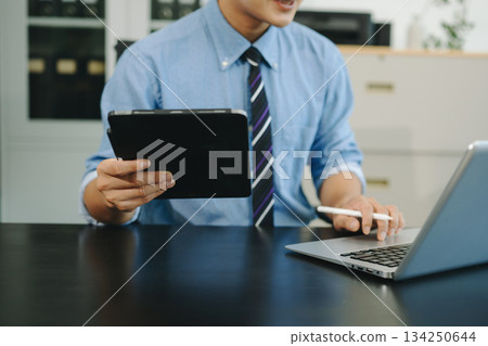 Confident businessman working on laptop, tablet and smartphone at her workplace Confident businessman working on laptop, tablet and smartphone at her workplace 134250644