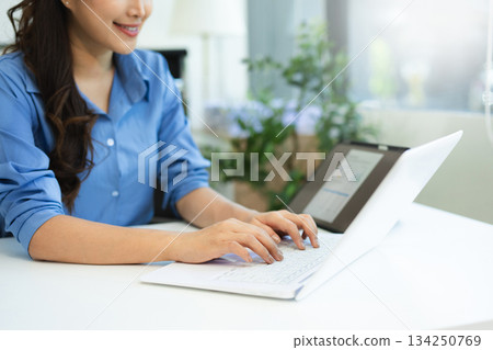 Business woman sitting front tablet ,laptop computer with financial graphs and statistics on monitor. 134250769