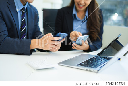 Businessman hand using laptop and tablet with social network diagram and two colleagues discussing data Businessman hand using laptop and tablet with social network diagram and two colleagues discussing data 134250784