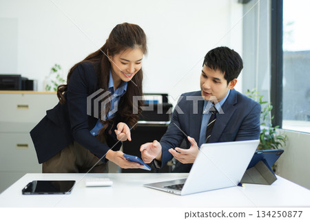 Asian businessman and woman workers talking on the smartphone and using laptop Professionals in Teamwork Finance, Marketing, and Success 134250877