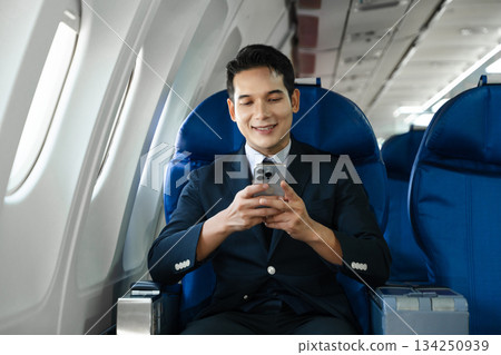Young Asian executive excels in first class, multitasking with digital tablet, laptop and smartphone. Travel in style, work with grace. Young Asian executive excels in first class, multitasking with digital tablet, laptop and smartphone. Travel in style, work with grace. 134250939