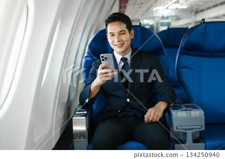 Young Asian executive excels in first class, multitasking with digital tablet, laptop and smartphone. Travel in style, work with grace. 134250940