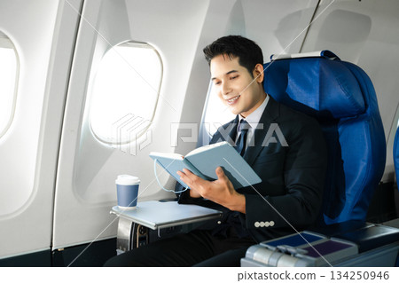 Young Asian executive excels in first class, multitasking with digital tablet, laptop and smartphone. Travel in style, work with grace. 134250946