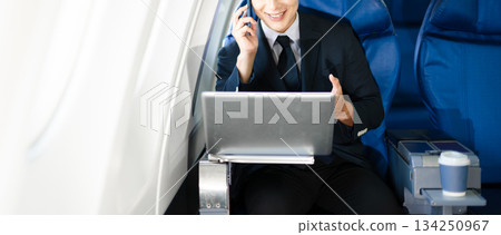 Confident businessman making a phone call in first class, blending luxury air travel with business, technology, and global networking opportunities. 134250967