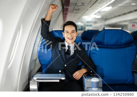 Smiling businessman in a suit giving a thumbs up while seated in first class, symbolizing success, confidence, and luxury air travel for business professionals. Smiling businessman in a suit giving a thumbs up while seated in first class, symbolizing success, confidence, and luxury air travel for business professionals. 134250980