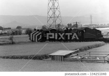 A double-headed steam locomotive travels through the countryside 134251040