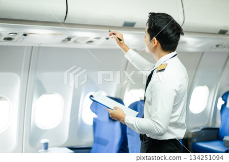 Professional airline pilot inspecting airplane cabin during safety check, perfect for aviation, travel, and airline safety concept stock photography Professional airline pilot inspecting airplane cabin during safety check, perfect for aviation, travel, and airline safety concept stock photography 134251094