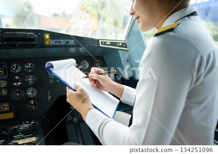Professional airline pilot in uniform inspecting cockpit control panels during safety checks, ideal for aviation, travel, and airline safety themes. Professional airline pilot in uniform inspecting cockpit control panels during safety checks, ideal for aviation, travel, and airline safety themes. 134251096