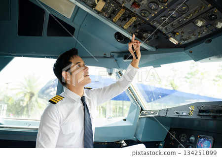 Professional airline pilot in uniform inspecting cockpit control panels during safety checks, ideal for aviation, travel, and airline safety themes. Professional airline pilot in uniform inspecting cockpit control panels during safety checks, ideal for aviation, travel, and airline safety themes. 134251099