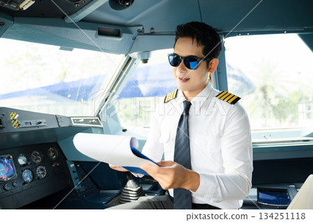 Professional airline pilot in uniform inspecting cockpit control panels during safety checks, ideal for aviation, travel, and airline safety themes. Professional airline pilot in uniform inspecting cockpit control panels during safety checks, ideal for aviation, travel, and airline safety themes. 134251118