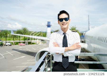 Airline pilot in uniform with sunglasses standing confidently outside airplane, ideal for aviation, travel, and professional pilot lifestyle imagery 134251126