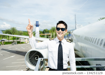 Airline pilot in uniform with sunglasses standing confidently outside airplane, ideal for aviation, travel, and professional pilot lifestyle imagery 134251129