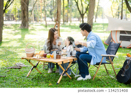 Happy parents and daughter Bakery and Bread Fruit enjoy  in a sunny garden. A joyful summer picnic full of love, food for family, outdoor 134251408