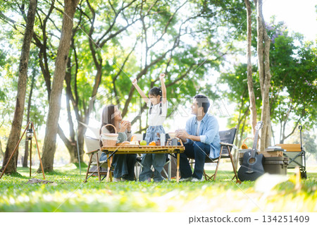 Happy parents and daughter Bakery and Bread Fruit enjoy  in a sunny garden. A joyful summer picnic full of love, food for family, outdoor 134251409