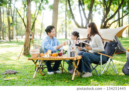 Happy parents and daughter Bakery and Bread Fruit enjoy  in a sunny garden. A joyful summer picnic full of love, food for family, outdoor 134251445