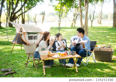 Happy parents and daughter Bakery and Bread Fruit enjoy  in a sunny garden. A joyful summer picnic full of love, food for family, outdoor 134251500
