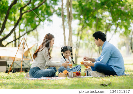 Happy parents and daughter Bakery and Bread Fruit enjoy in a sunny garden. A joyful summer picnic full of love, food for family, outdoor Happy parents and daughter Bakery and Bread Fruit enjoy in a sunny garden. A joyful summer picnic full of love, food for family, outdoor 134251537