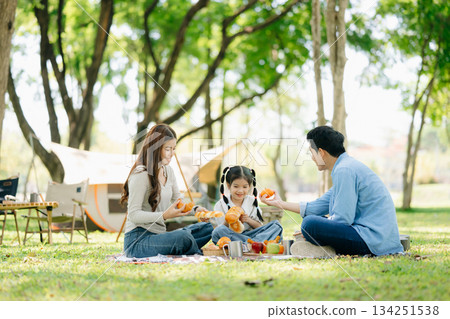 Happy parents and daughter Bakery and Bread Fruit enjoy in a sunny garden. A joyful summer picnic full of love, food for family Happy parents and daughter Bakery and Bread Fruit enjoy in a sunny garden. A joyful summer picnic full of love, food for family 134251538