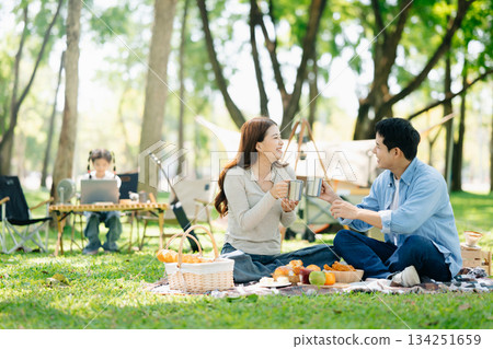 Asian couple enjoys a peaceful camping morning with coffee, breakfast, music, and devices in nature Asian couple enjoys a peaceful camping morning with coffee, breakfast, music, and devices in nature 134251659