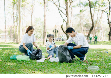 Asian parents and child collect bottles at the park, sharing love, teamwork, and care. A green lifestyle moment promoting recycling, unity 134251716
