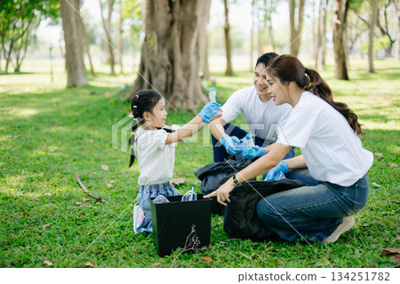 Asian parents and child collect trash in the forest, promoting recycling, unity, and ecology. A heartwarming scene of love, care, teamwork 134251782