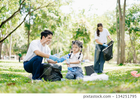 Asian parents and child collect trash in the forest, promoting recycling, unity, and ecology. A heartwarming scene of love, care, teamwork 134251795