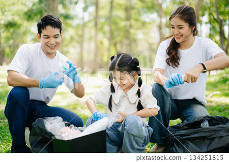 Asian parents and child collect bottles at the park, sharing love, teamwork, and care. A green lifestyle moment promoting recycling, unity 134251815