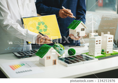 Sustainable architects presenting green building models, solar panels, and recycling symbols. Future clean energy and smart city 134251976
