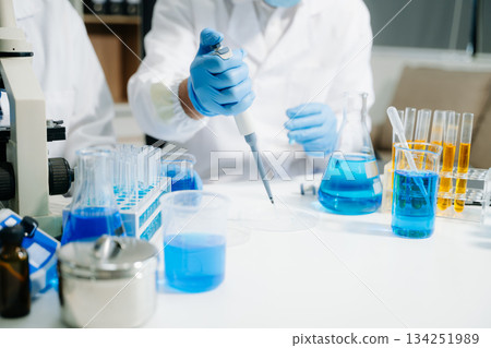 Two scientists in a high-tech lab analyzing biochemical samples, using micro pipettes Two scientists in a high-tech lab analyzing biochemical samples, using micro pipettes 134251989