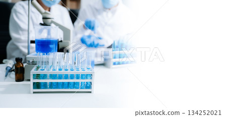 scientists in lab coats conducting research, handling glassware, and working with chemicals 134252021