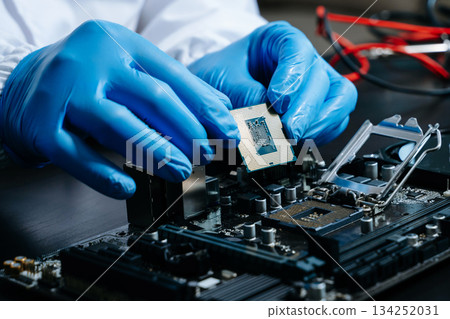 The technician is putting the CPU on the socket of the computer motherboard. electronic engineering electronic 134252031