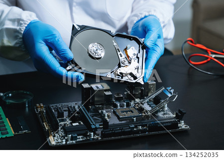 Hard disk drive on the technician's desk and a computer motherboard as a component. the concept of data, hardware 134252035