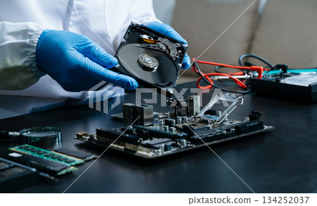 Hard disk drive on the technician's desk and a computer motherboard as a component. the concept of data, hardware Hard disk drive on the technician's desk and a computer motherboard as a component. the concept of data, hardware 134252037