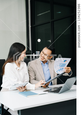 Two business workers talking on the smartphone and using laptop at the office. Two business workers talking on the smartphone and using laptop at the office. 134252366