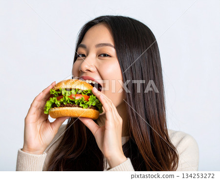 A young woman eating a hamburger 134253272