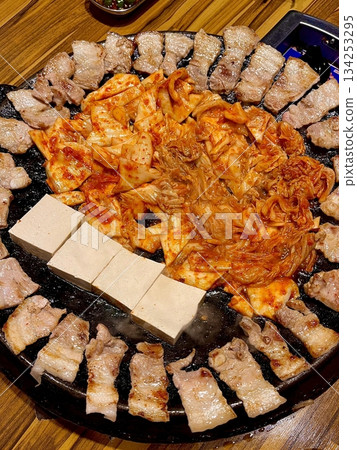 Juicy grilled samgyeopsal paired with savory mushrooms and tangy, sizzling kimchi, creating a perfect balance of rich, earthy, and spicy flavors in every delicious, mouthwatering bite. 134253295