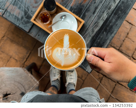 Hot coffee. Holding a hot latte in a mug from the cafe. 134253392