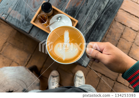 Hot coffee. Holding a hot latte in a mug from the cafe. 134253393