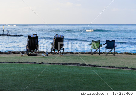 在威基基海灘，人們躺在沙灘椅上放鬆身心，俯瞰著大海。 134253400