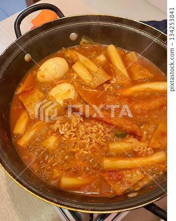 A hearty bowl of Budaejjigae (Korean Army Stew), filled with sausage, tofu, kimchi, and noodles in a spicy broth. This flavorful dish brings warmth and comfort, perfect for sharing. 134253841