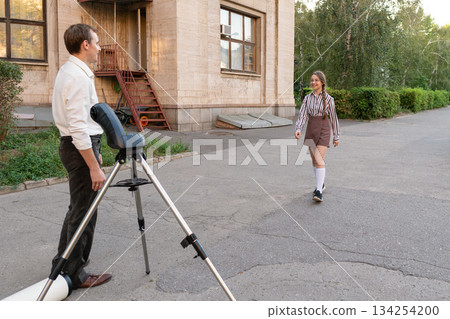 Two people preparing for telescope observation outdoors 134254200