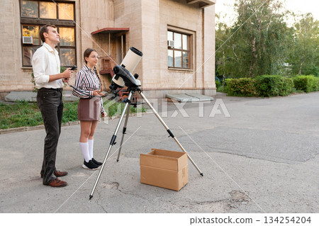 Teacher and student preparing telescope for sky observation 134254204