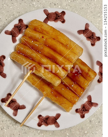 Delicious tteok kkochi, skewered rice cakes grilled to perfection and coated with a sweet, savory sauce. A popular Korean street food, perfect for snacking and sharing. Warm, flavorful, and satisfying Delicious tteok kkochi, skewered rice cakes grilled to perfection and coated with a sweet, savory sauce. A popular Korean street food, perfect for snacking and sharing. Warm, flavorful, and satisfying 134255153
