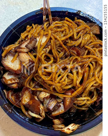 Classic jajangmyeon with thick noodles in a rich black bean sauce, garnished with sliced cucumber and sesame seeds. A beloved Korean-Chinese comfort dish, full of savory depth and flavor. 134255155