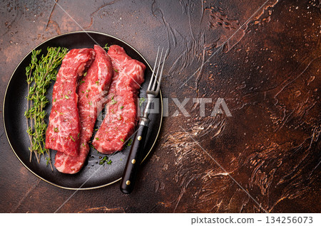 Tri tip steaks, Raw marbled beef meat on plate with herbs. brown background. top view 134256073