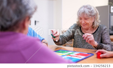 Elderly women playing board game in nursing home 134256213