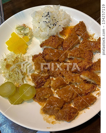 Crispy tonkatsu, a Japanese-style breaded and deep-fried pork cutlet, served with shredded cabbage and drizzled with savory sauce. A delightful balance of crunchy texture and juicy meat. 134257119
