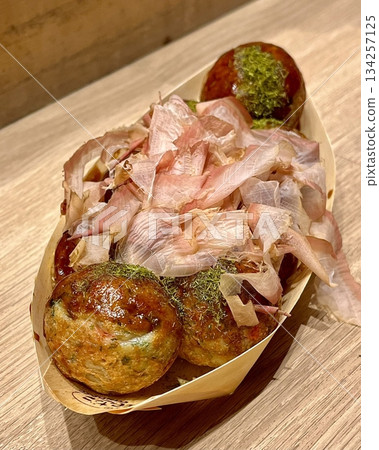 Takoyaki, a popular Japanese street food, are crispy round dough balls filled with octopus, tempura bits, and pickled ginger, topped with takoyaki sauce, bonito flakes, and aonori. Takoyaki, a popular Japanese street food, are crispy round dough balls filled with octopus, tempura bits, and pickled ginger, topped with takoyaki sauce, bonito flakes, and aonori. 134257125