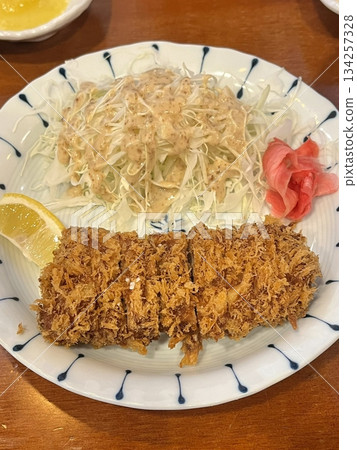 Crispy tonkatsu, a Japanese-style breaded and deep-fried pork cutlet, served with shredded cabbage and drizzled with savory sauce. A delightful balance of crunchy texture and juicy meat. Crispy tonkatsu, a Japanese-style breaded and deep-fried pork cutlet, served with shredded cabbage and drizzled with savory sauce. A delightful balance of crunchy texture and juicy meat. 134257328